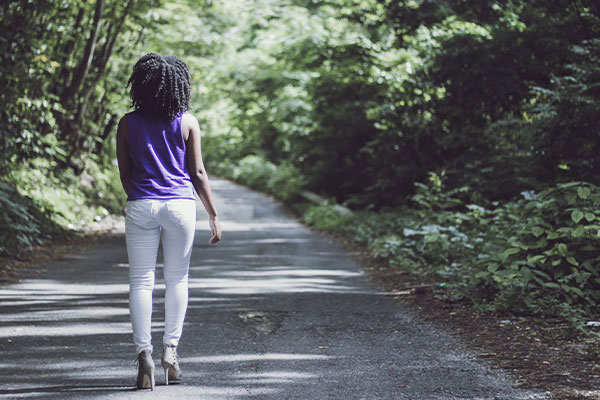 Photo of a woman walking in a park in Kirkwood, MO. Overwhelmed moms, moms of teens, and postpartum counseling is here for you at Marble Wellness in St. Louis, MO.