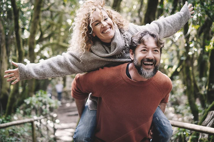 Happy couple doing a piggy back ride at a park. Couples and marriage therapy in St. Louis can bring back the play and adventure in your relationship. Call today to start couples counseling in West County, MO!