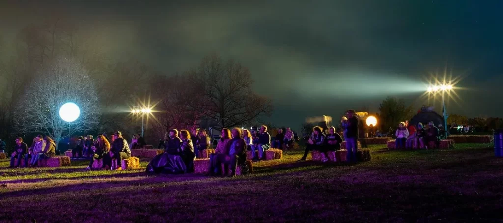 People sitting and watching at night at Laumeier Sculpture Park. Maternal mental health therapists for moms in Kirkwood recommend getting out and experiencing STL in the Fall. 