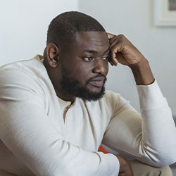 Photo of a black man with a worried and contemplative look before searching for "anxiety treatment in St. Louis, MO" on his laptop. There is hope to feel better after counseling for anxiety with Marble Wellness. We offer in-person sessions, telehealth in Missouri, and park therapy too.