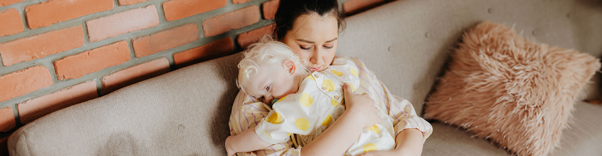 Photo of a mother holding her child affectionately while letting on a tired and worried expression. Our therapists offer counseling for Overwhelmed Moms in St. Louis, MO 63011.