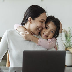 Photo of a cute little kid hugging her mom while she's working. You can feel better after maternal mental health counseling in St. Louis, MO, and online therapy for women in Missouri at Marble Wellness!