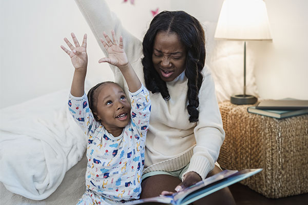 Photo of a mother and child playing and laughing while reading a bedtime story. Counseling for moms and maternal overwhelm in St. Louis, MO can help. Marble Wellness provides in-person and online therapy in Missouri for maternal mental health counseling in St. Louis, MO.