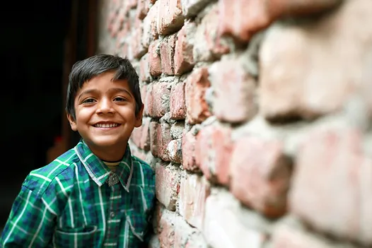 A young boy stands next to a brick wall. Marble Wellness offers child therapy in St. Louis, MO, as well as family therapy and therapy for teens.