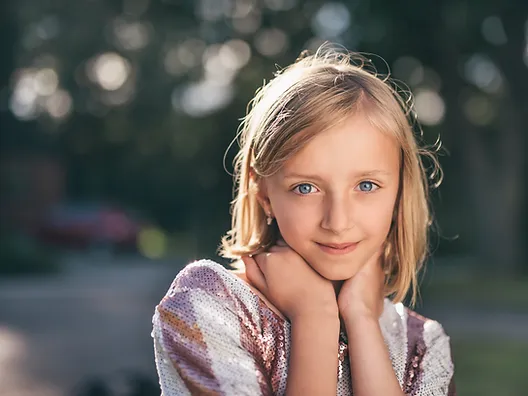 A young girl looks at the camera. Mental health support for kids is available through play therapy in West County, MO at Marble Wellness. Child therapy is available for kids, preteens, and teens.