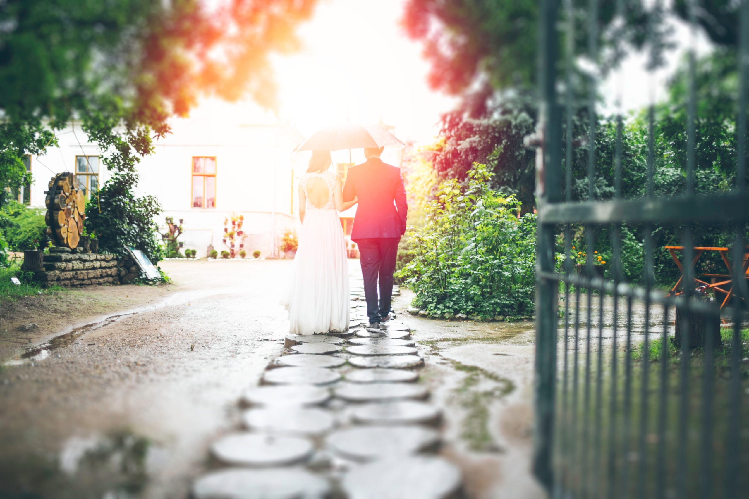 A husband and wife on their wedding day walking down a cobblestone street with an umbrella. Couples and marriage therapy in St. Louis can help you prepare for your big day. Reach out today to setup an appointment.