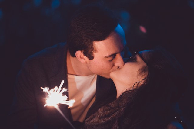 Man and woman kissing while holding a sparkler. Couples therapy in St. Louis can help reignite that spark in your relationship.