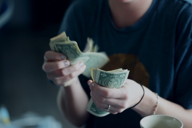 Person counting dollar bills. Financial matters can cause tension in relationships. Meet with a licensed couples counselor to help alleviate stress.