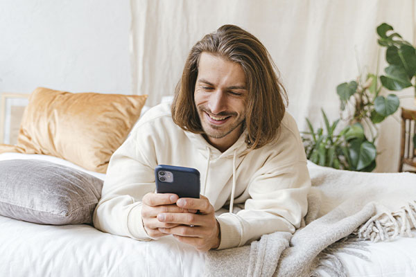 Photo of a man looking at his phone and smiling. Anxiety treatment in Chicago, IL can help you build happier and more fulfilling relationship with yourself and others.