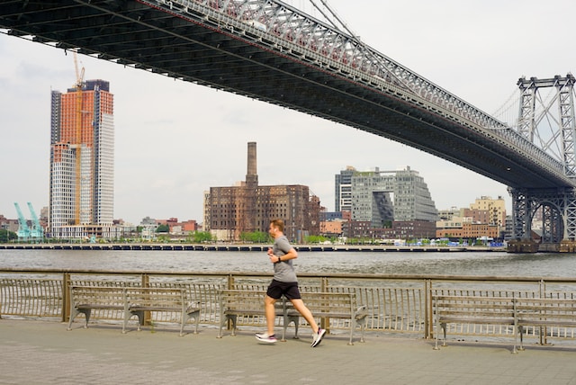 Man in workout clothes jogging underneath a bridge in the city near water. Carving out time for yourself during the day can help balance work and family life. Call to schedule an appointment with a counselor specializing in men's mental health.
