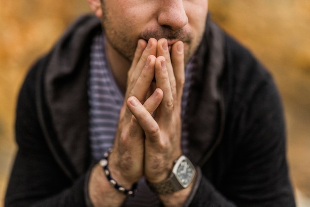 Trendy man in cardigan with hands on chin appearing to be deep in thought. Therapy is a judgement free zone where you can express your thoughts and emotions. Marble Wellness offers therapy for men in St. Louis.