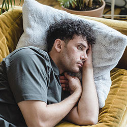 Photo of a man lying in the sofa with a sad expression. There is hope after therapy for depression in Chicago, IL at Marble Wellness 63122 | forrest glen 60630 | Lincoln Park is 60614 | north center 60613 | 60618.