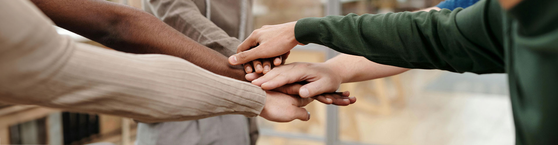 Photo of the group of people with their hands together in a circle. At Marble Wellness, you can find the support and connection you deserve through group therapy in St. Louis.