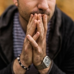 Trendy man in cardigan with hands on chin appearing to be deep in thought. Therapy is a judgement free zone where you can express your thoughts and emotions. Marble Wellness offers therapy for men in St. Louis.