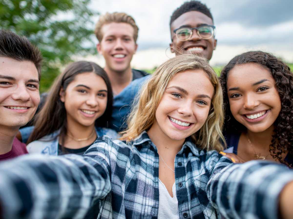 Big group of teenagers smiling and looking at the camera for a group photo. Therapy for teenagers in St. Louis, MO can help your teenager feel more balanced and "normal" during a time that often feels totally out of control. Meet with a teen therapist in Ballwin, MO today!