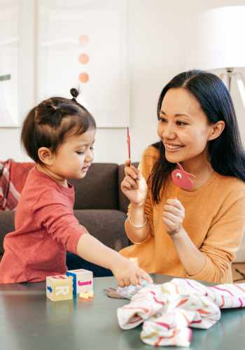 Asian mom sitting with her toddler daughter after seeking parent coaching to ensure you have the connection created to facilitate strong, healthy parental bonds in Ballwin, MO and beyond. 