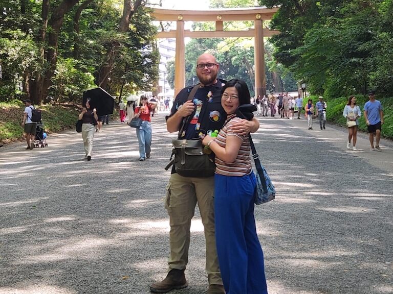 Marble Wellness Therapist Harue, standing with her husband near trees in Japan looking at the camera. Meet with a Missouri online therapist for children, teens young adults, moms and more here!