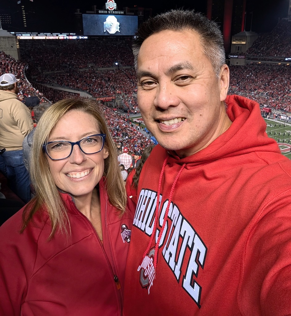 Kristi Machica, STL Therapist for moms in Ballwin, MO Kristi Machica, STL Therapist for moms in Ballwin, MO poses for a photo with her husband at an Ohio State football game.